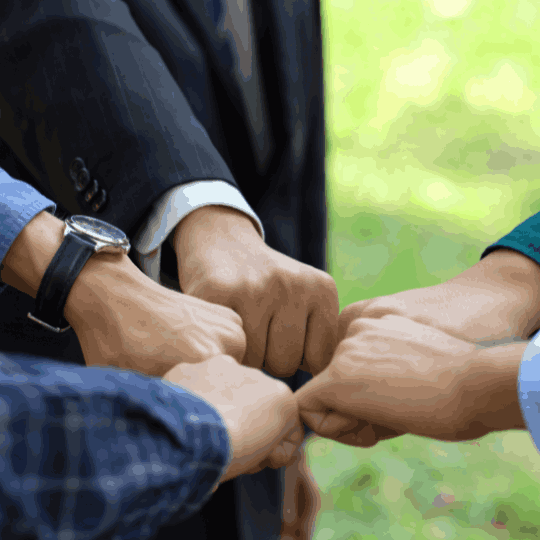 Close-up of four hands meeting in a fist-bump gesture, symbolizing teamwork, collaboration, and strong partnership between MaxxGro and its agrochemical distribution network or farmers.