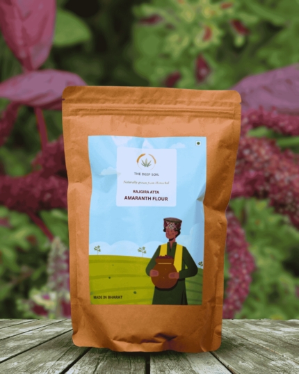 The Deep Soil Amaranth Flour Rajgira Atta package on wooden table with pink amaranth crop background