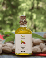 The Deep Soil Cold-Pressed Almond Oil 100ml glass bottle with a cork stopper and raw almonds in a blurred nature background