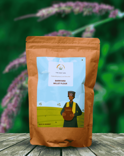 The Deep Soil Barnyard Millet Flour package on wooden table with purple-tinged millet crop background