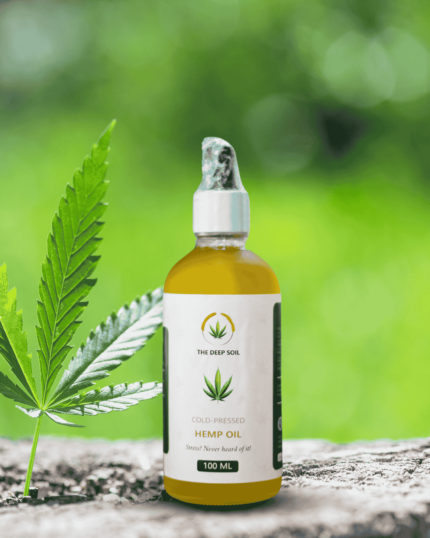 The Deep Soil Cold-Pressed Hemp Oil 100ml dropper bottle with a fresh green hemp leaf and blurred forest background