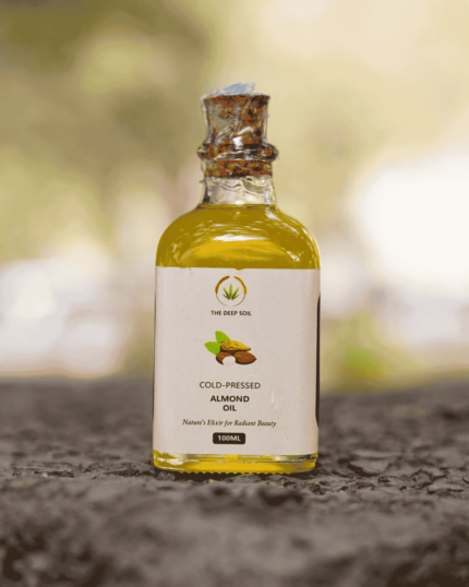 100ml bottle of The Deep Soil Cold-Pressed Almond Oil on a stone surface with nature background