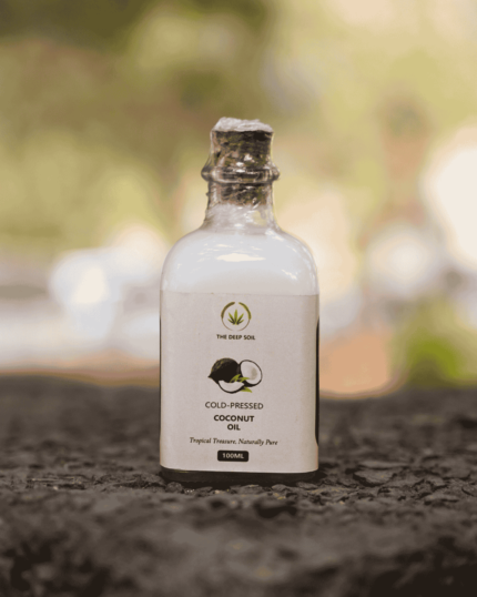 The Deep Soil Cold-Pressed Coconut Oil 100ml bottle on stone surface with nature background