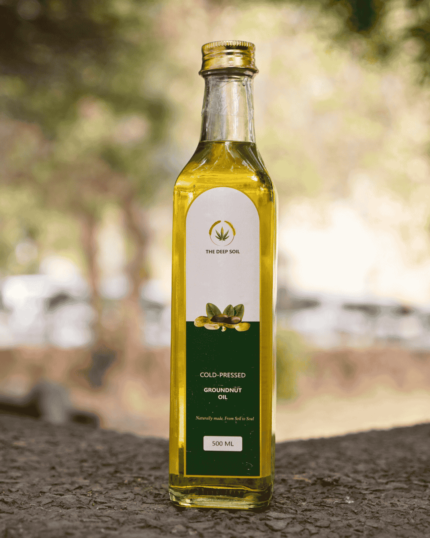 500ml bottle of The Deep Soil Cold-Pressed Groundnut Oil on a stone surface with nature background