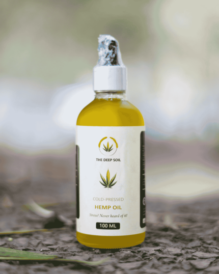 100ml bottle of The Deep Soil Cold-Pressed Hemp Oil on a stone surface with nature background