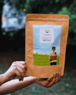 Hands holding The Deep Soil Kodo Flour Gharat Ka Kodra Ka Atta package with nature background