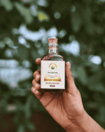 Hand holding 100ml bottle of The Deep Soil Pahadi Shahad Unprocessed Raw Honey with green nature background