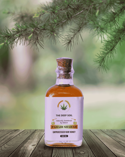 The Deep Soil Pahadi Shahad Unprocessed Raw Honey 100ml bottle on wooden table with pine branches