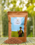 The Deep Soil Red Rice Pahadi Laal Chawal package with a pile of raw grains on a wooden table and sunlit forest background